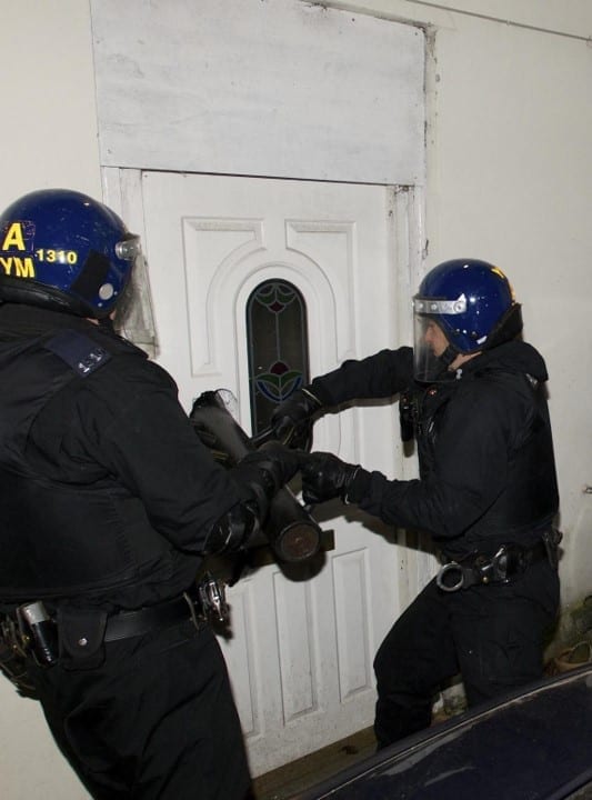 Police raid a house; image by West Midlands police, via Flickr, CC BY-SA 2.0, cropped for space.