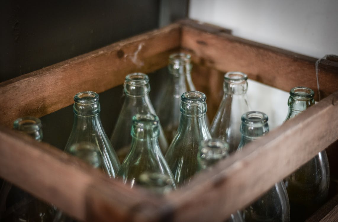 A wooden crate holding empty, clear glass bottles.