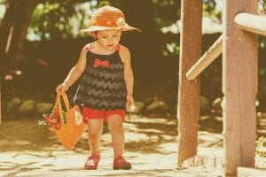 Little girl wearing red shorts, black top, and straw hat walking; image by Miguel R. Perez, via Pixabay.com.