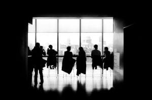 People sitting at a long conference table in front of windows; image by Samuel Zeller, via Unsplash.com.