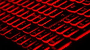 Computer keyboard with black keys backlit in red; image by Taskin Ashiq, via Unsplash.com.