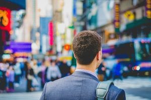 Man in blue suit with brief case seen from the back; image by Saulo Mohana, via Unsplash.com.