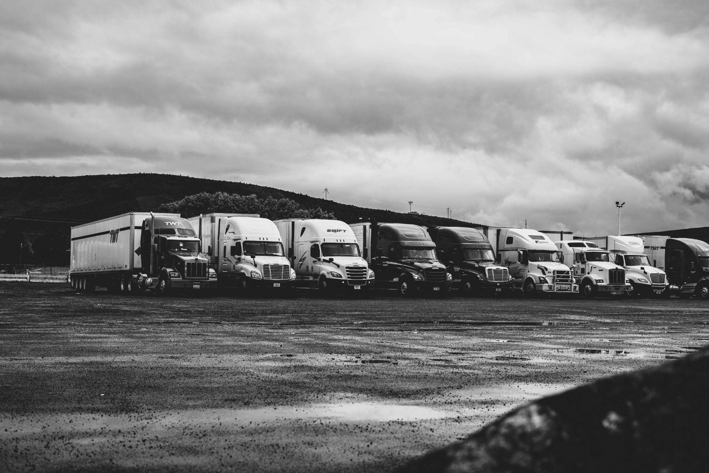 Bladk and white photo of parked trucks in a line; image by Kevin Bidwell, via Pexels.com.
