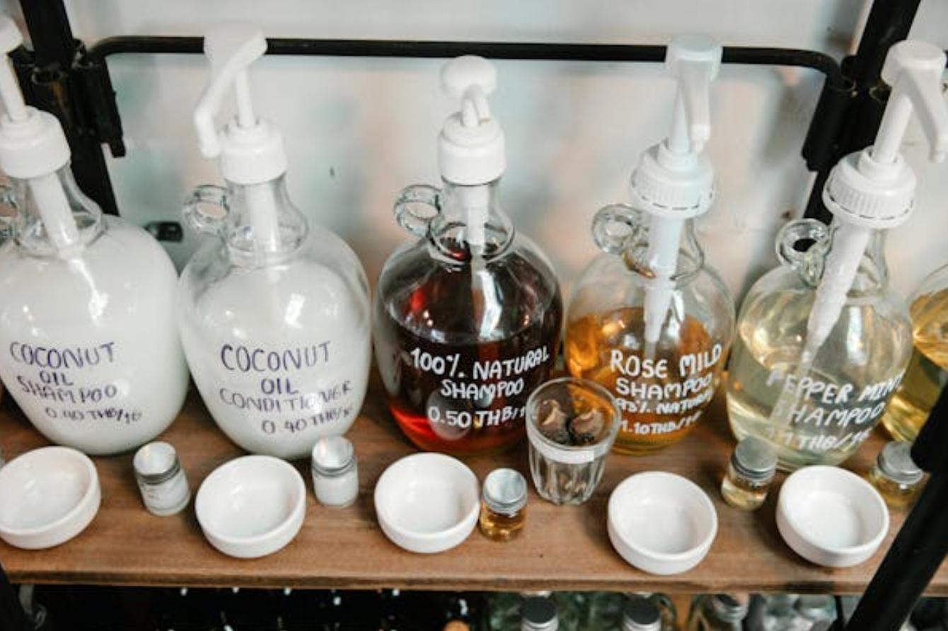 Glass refillable pump bottles of shampoo on a shelf; image by Sarah Chai, via Pexels.com.