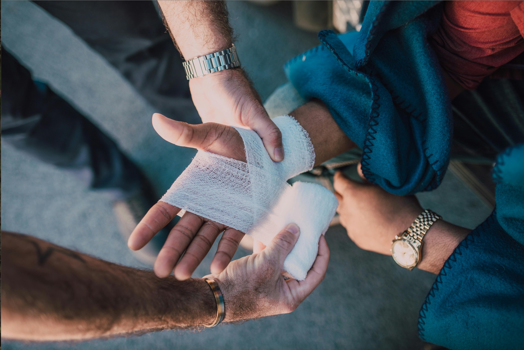 Man bandaging another person's hand; image by RDNE Stock project, via Pexels.com.