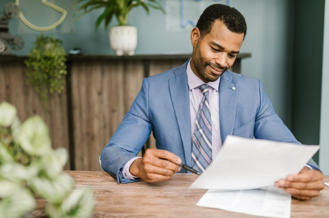 Man in blue suit jacket holding paper and pen; image by RDNE Stock project, via Pexels.com.