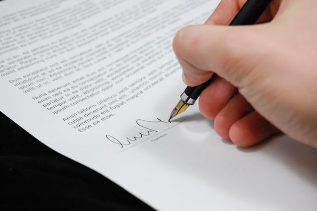 Person signing document; image by Pixabay, via Pexels.com.