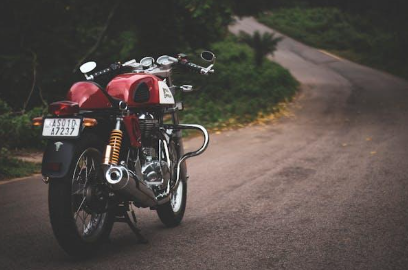 Red motorcycle parked on farm road; image by Pragyan Bezbaruah, via Pexels.com.