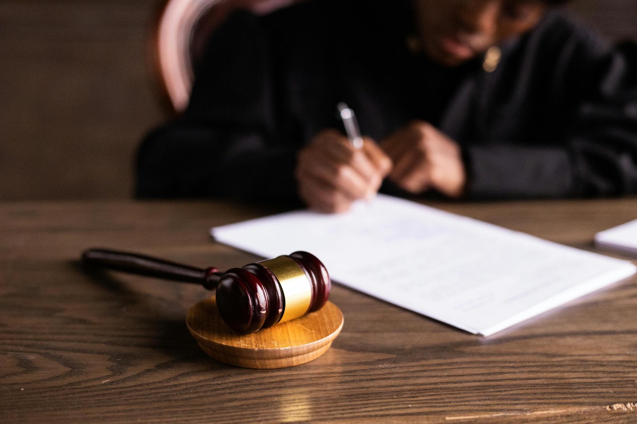 Judge signing paperwork; image by KATRIN BOLOVTSOVA, via Pexels.com.