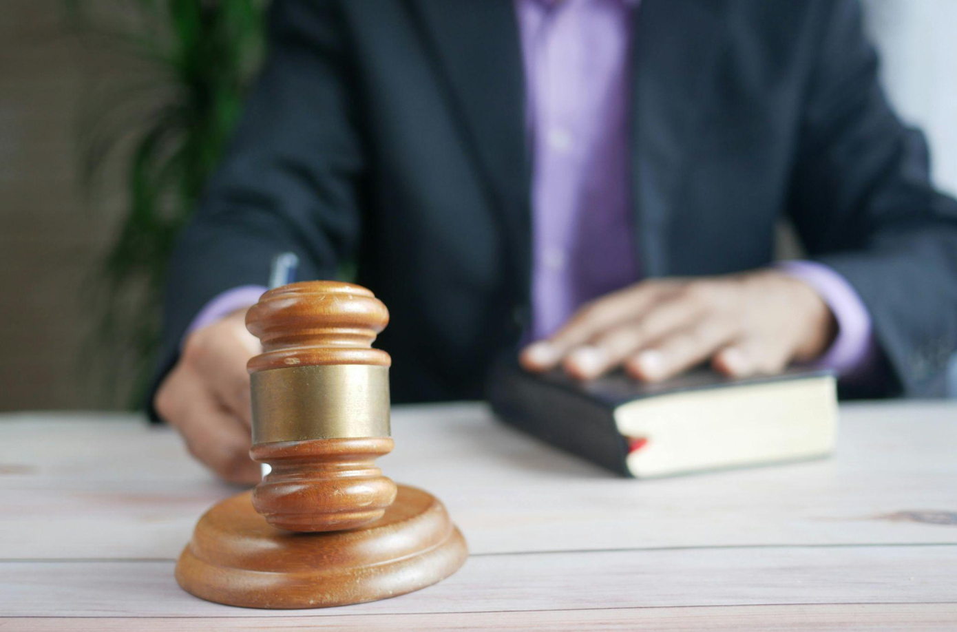 Man behind desk holding brown gavel; image by Towfiqu barbhuiya, via Pexels.com.