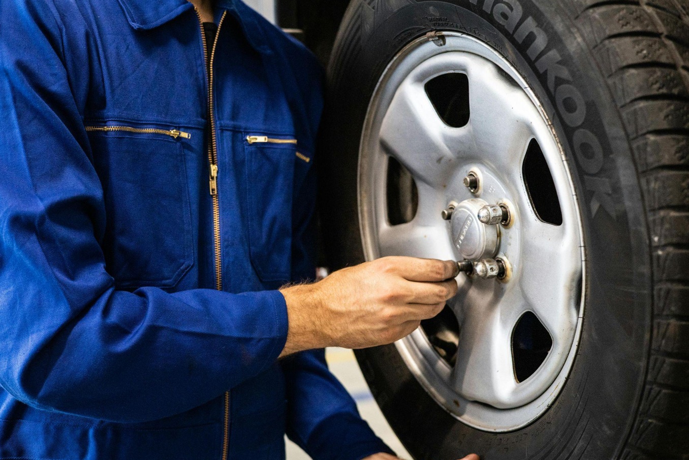 Man replacing lug nuts on a tire; image by Artem Podrez, via Pexels.com.