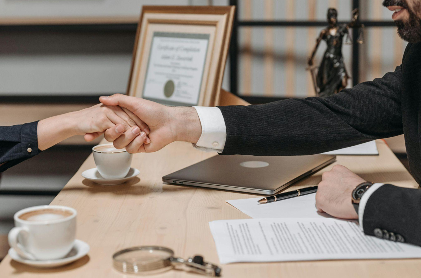 People shaking hands across a desk; image by Pavel Danilyuk, via Pexels.com.