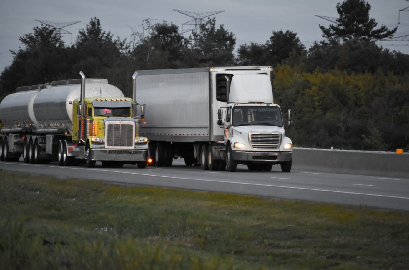 Two semi-trucks driving side by side; image by Wirestock, via Freepik.com.