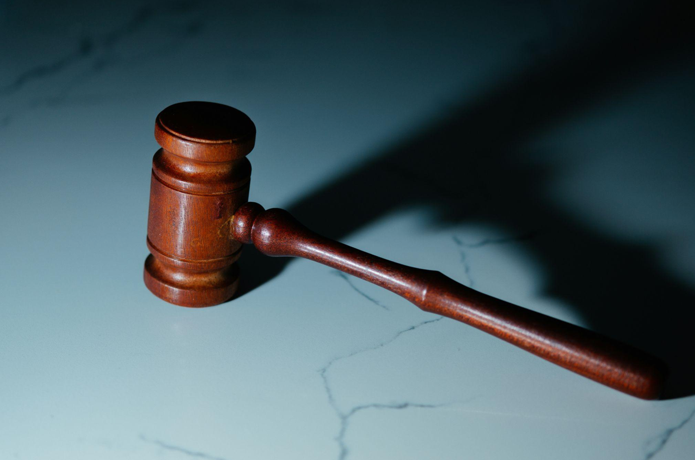 Wooden gavel on white marble tabletop; image by Wesley Tingey, via Unsplash.com.