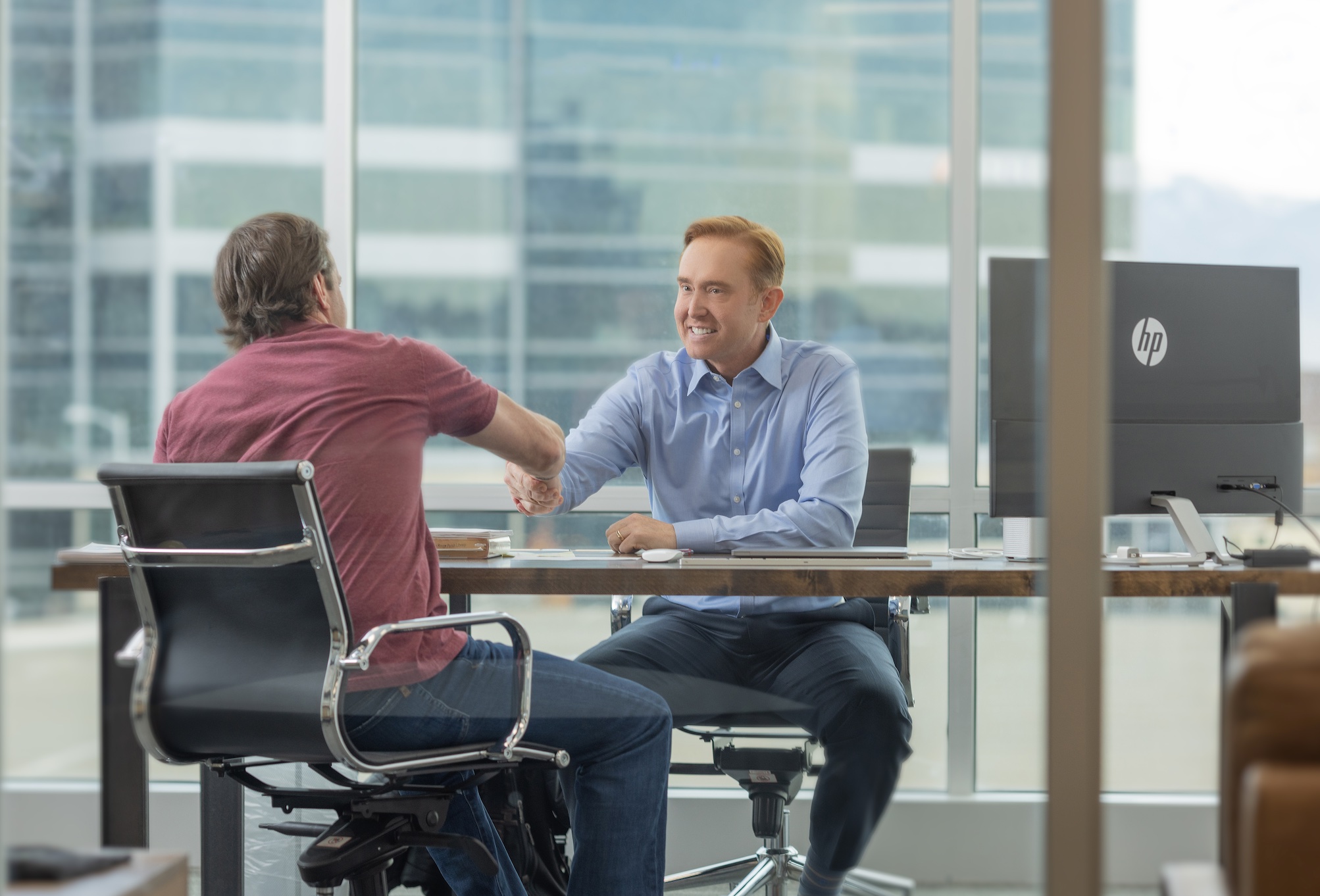 Brian Stewart at his desk, shaking a client's hand; image courtesy of author.