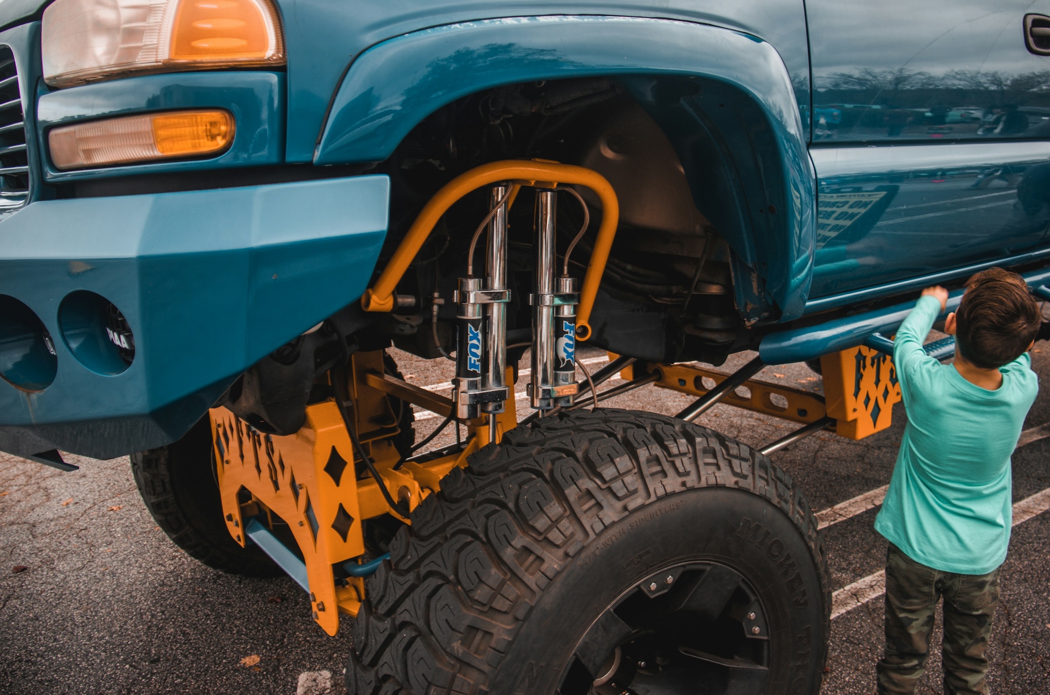 Lifted truck with admiring kid; image by Ben Duke, via Unsplash.com.