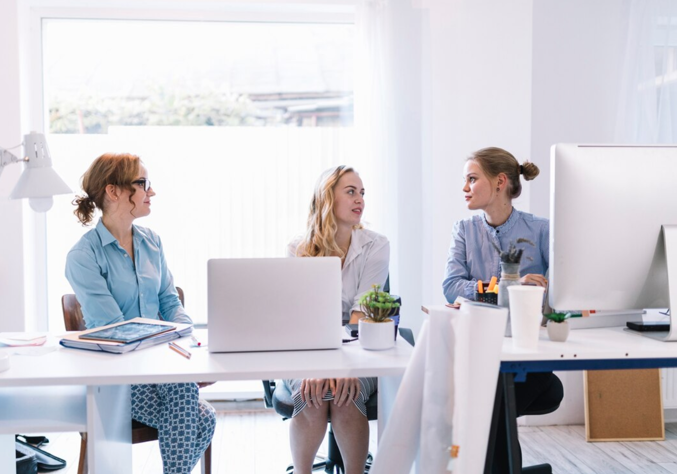 Three young businesswomen sitting together; image by Freepik, via Freepik.com.