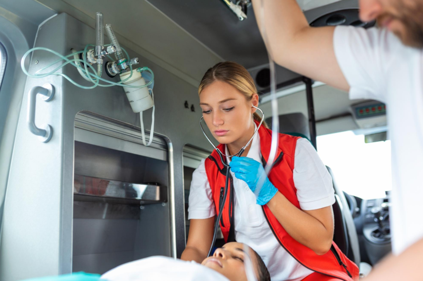 Two EMTs and a patient in the back of an ambulance; image by stefamerpik, via Freepik.com.