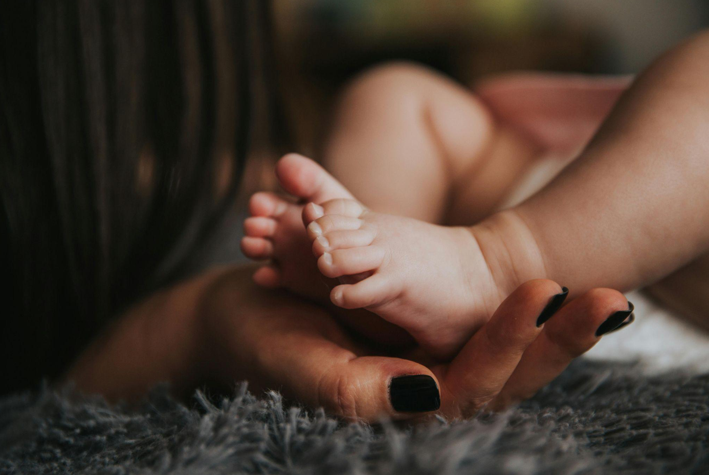 Woman holding a baby's feet in selective focus photography; image by Pixabay, via Pexels.com.