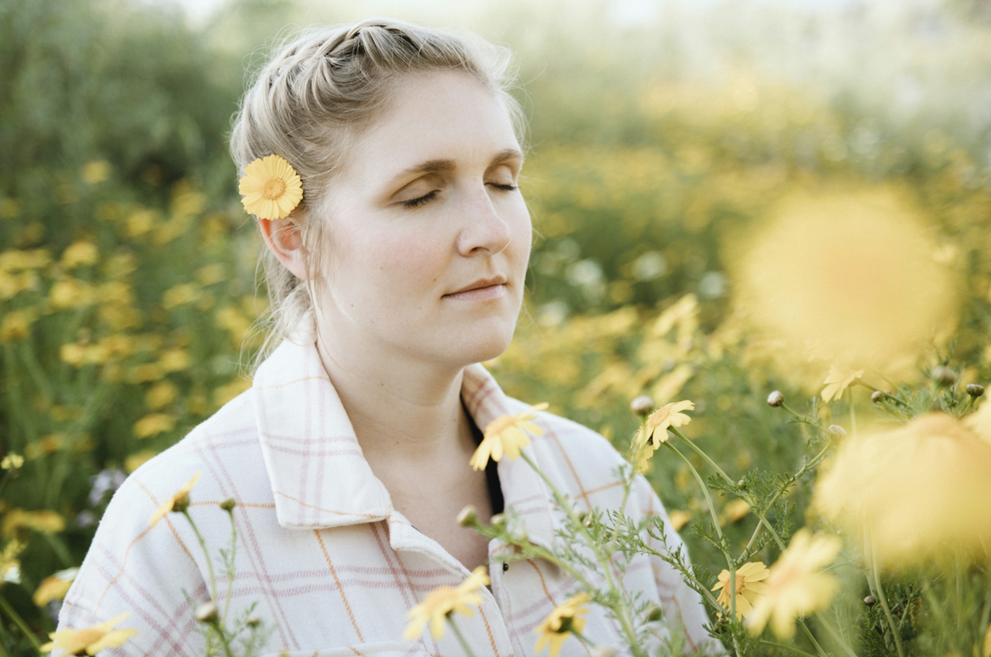 Woman standing in a field of yellow flowers; image by Tim Mossholder, via Unsplash.com.