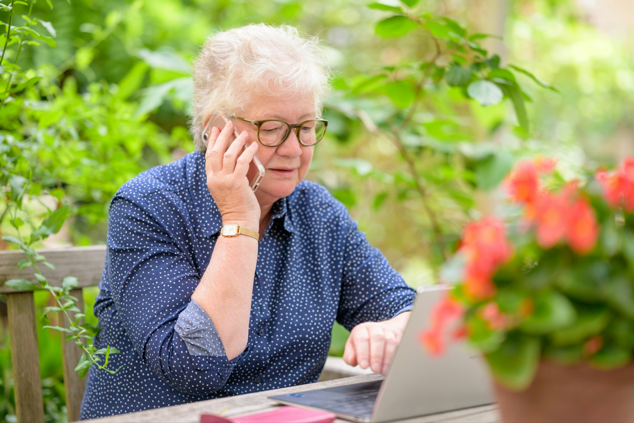 Old woman on cellphone using laptop; image by Centre for Ageing Better, via Unsplash.com.