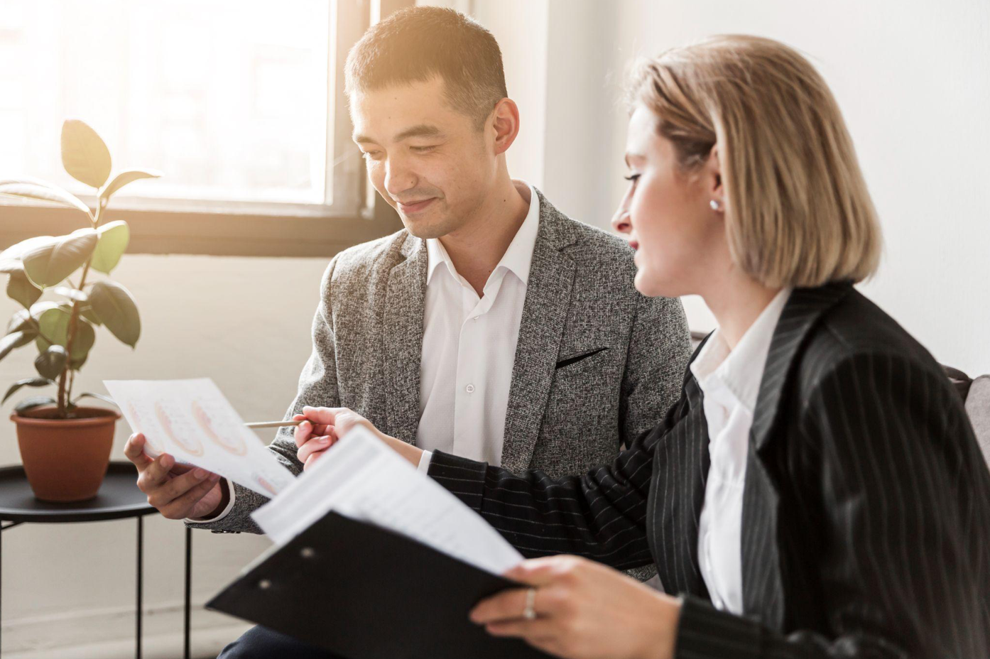 Two people discussing paperwork; image by Freepik, via Freepik.com.