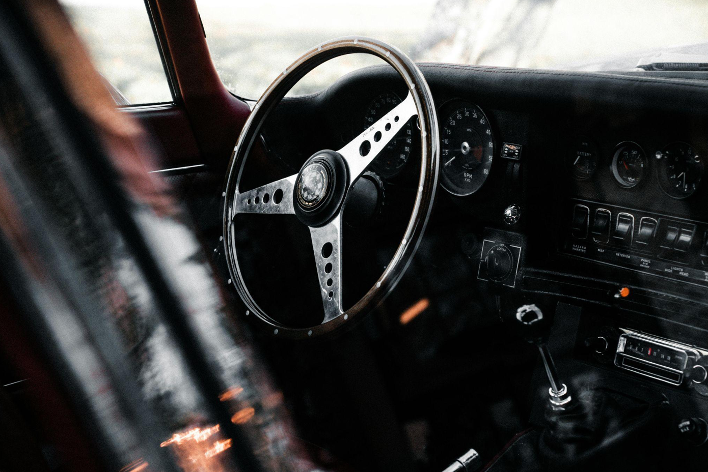 Vintage car showing steering wheel and dashboard; image by Connor McManus, via Pexels.com.