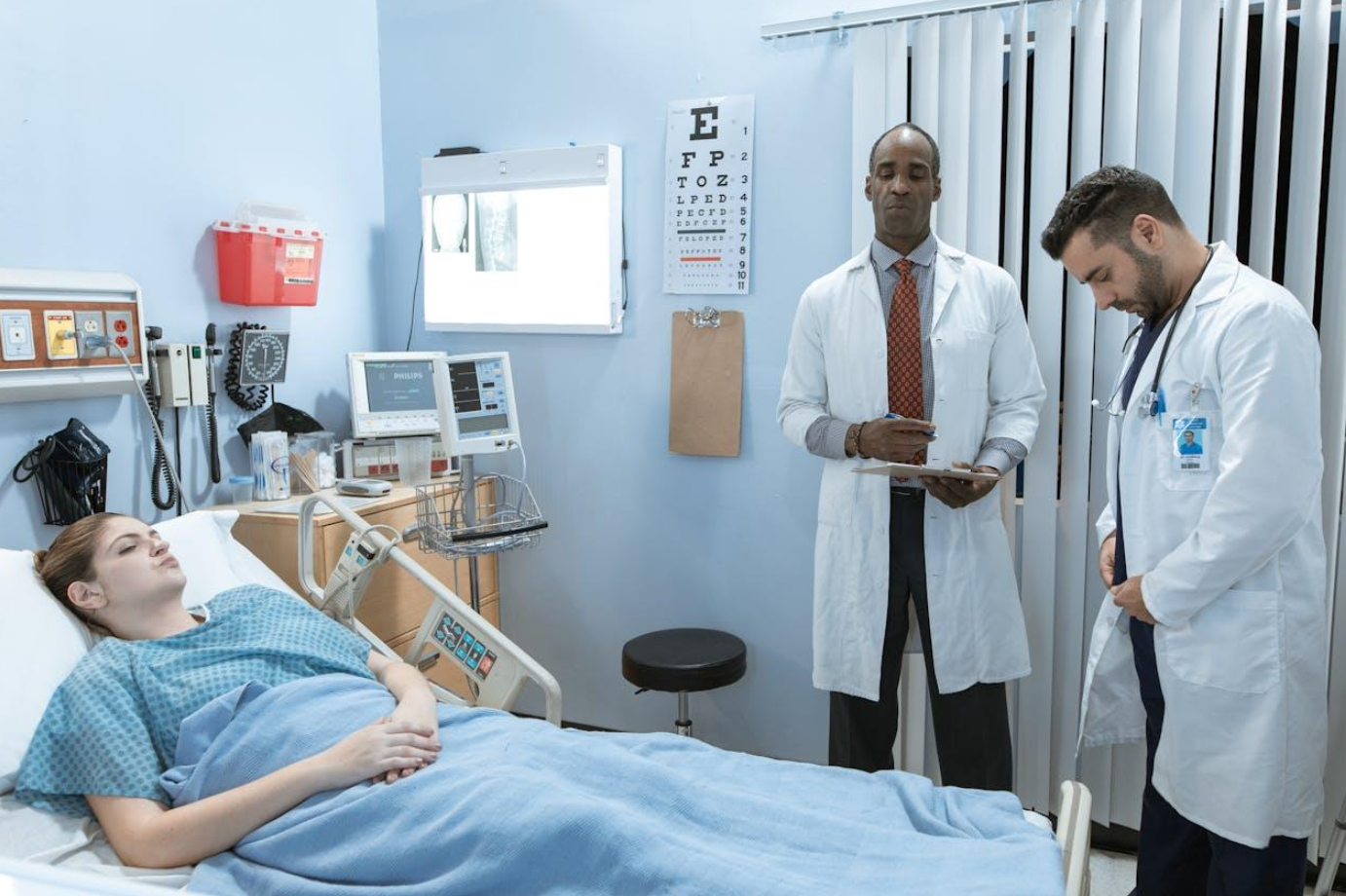 Doctors standing by patient bed; image by RDNE Stock project, via Pexels.com.