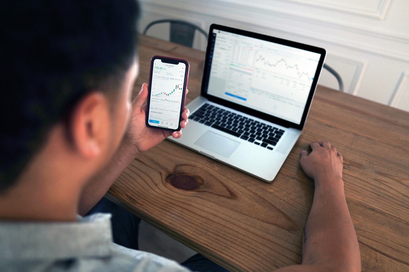 Man using smartphone and laptop to look at fund performance; image by Joshua Mayo, via Pexels.com.