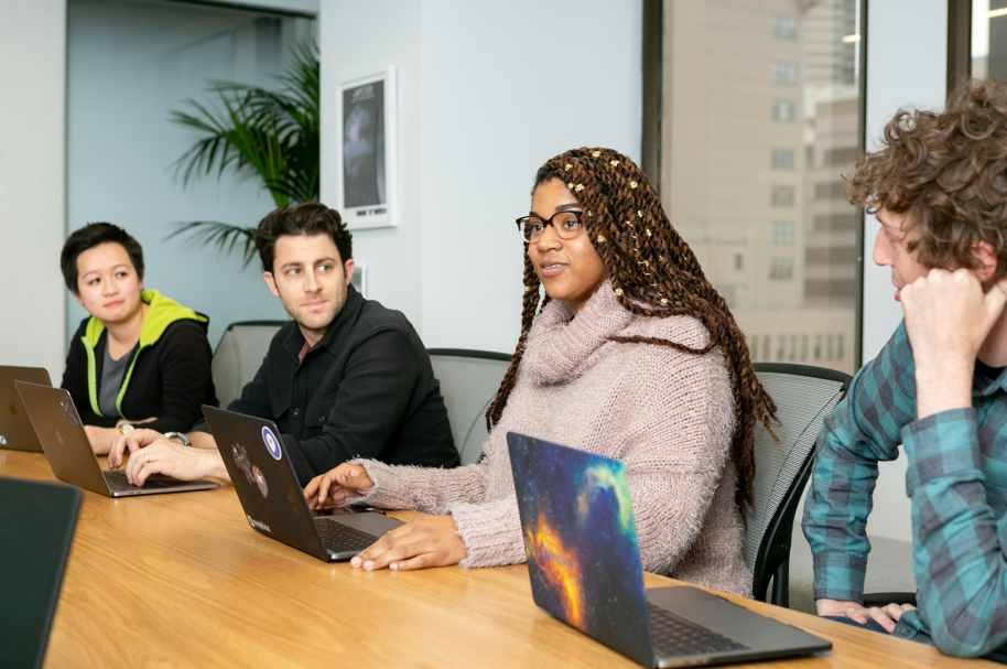 People with laptops in a meeting; image by Mapbox, via Unsplash.com.