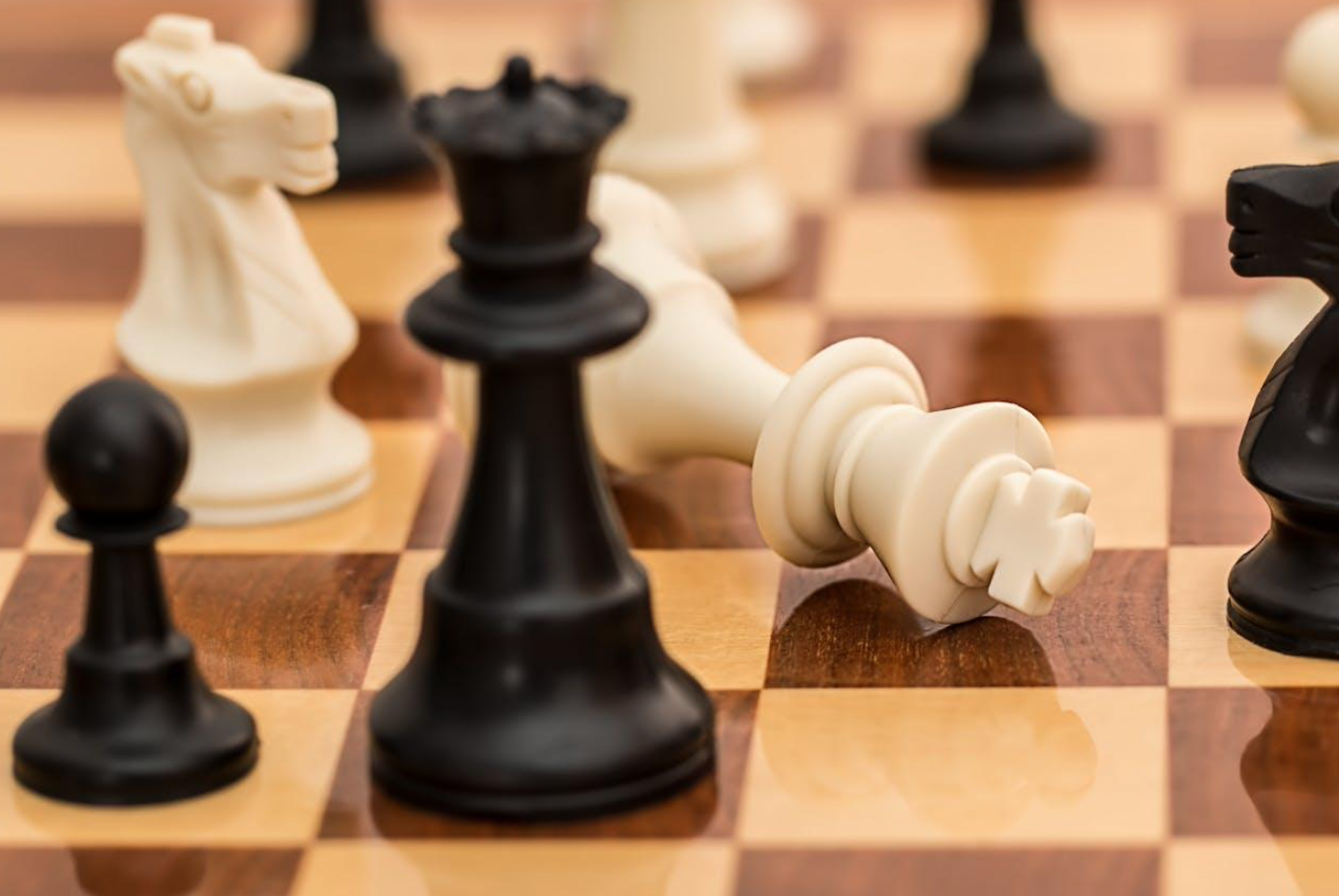 Black and white chess pieces on brown chess board; image by Pixabay, via Pexels.com.