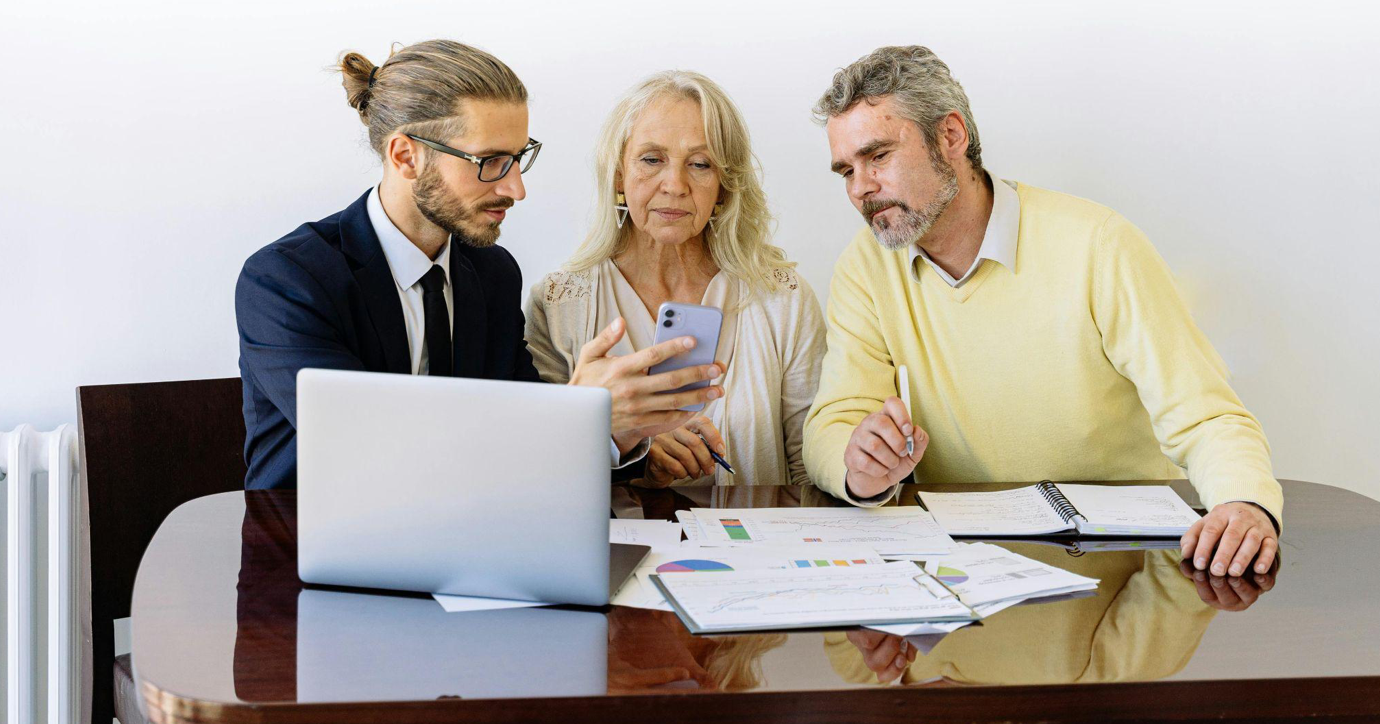 Older man and woman at table with younger man, reviewing paperwork; image by Antoni Shkraba, via Pexels.com.